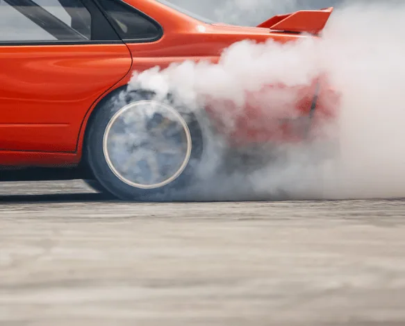 Red performance car creating tyre smoke